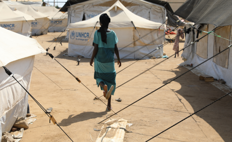 A woman walking among tents.